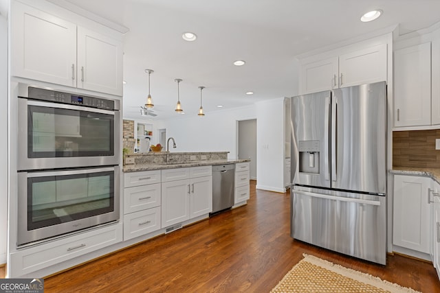 kitchen featuring a sink, stainless steel appliances, a peninsula, and white cabinetry