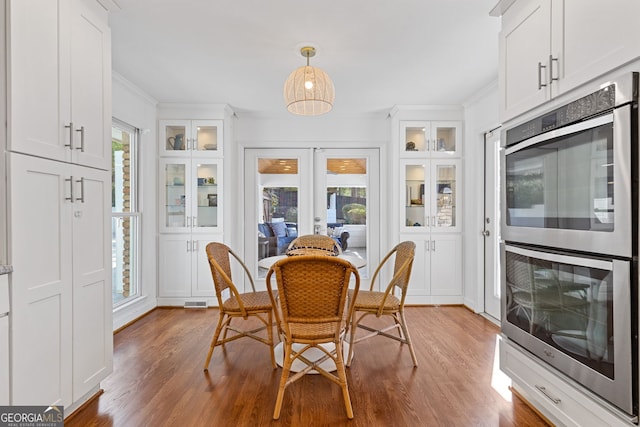 dining room with crown molding, plenty of natural light, french doors, and wood finished floors