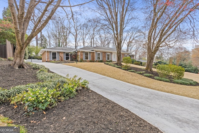 view of front of home with brick siding, driveway, a front yard, and fence