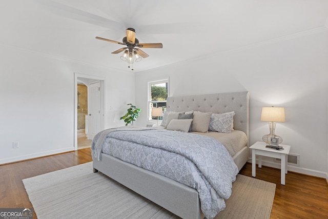 bedroom with crown molding, wood finished floors, baseboards, and visible vents