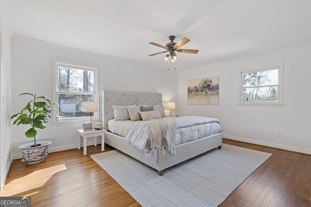 bedroom featuring baseboards, multiple windows, wood finished floors, and crown molding