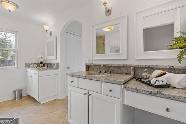 bathroom featuring two vanities, a sink, crown molding, tile patterned flooring, and baseboards