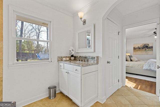 ensuite bathroom with crown molding, baseboards, tile patterned floors, vanity, and a ceiling fan