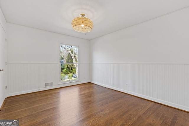 spare room featuring visible vents, a wainscoted wall, and wood finished floors