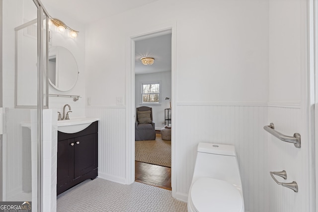 bathroom featuring vanity, toilet, ensuite bath, and wainscoting