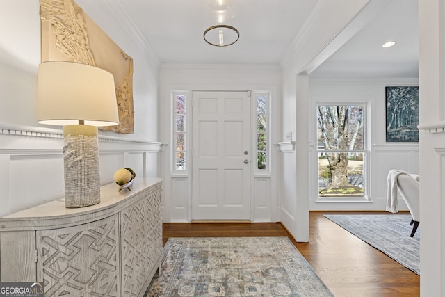 entrance foyer featuring wood finished floors, crown molding, and a decorative wall