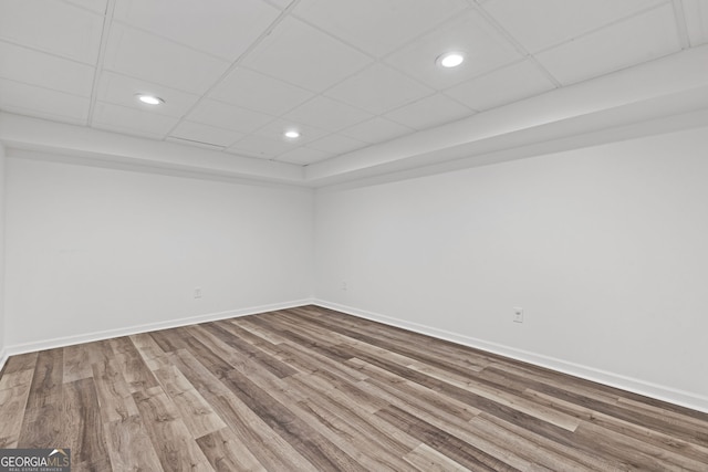 empty room featuring recessed lighting, a paneled ceiling, baseboards, and wood finished floors