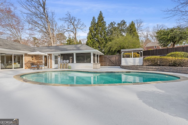 view of pool featuring a patio area, fence, a fenced in pool, and a sunroom