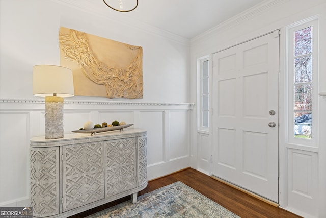 entryway featuring a decorative wall, a wainscoted wall, crown molding, and dark wood-style flooring