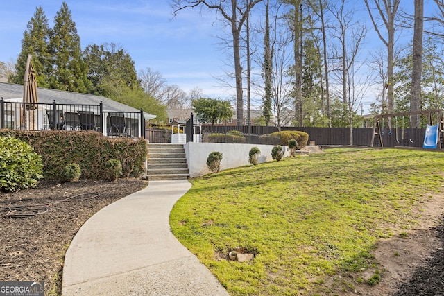 view of yard featuring fence private yard, a playground, and stairs