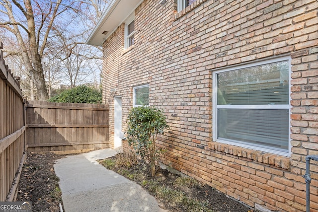 view of side of home with brick siding and a fenced backyard