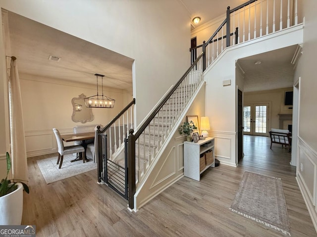 stairs with an inviting chandelier, crown molding, a decorative wall, and wood finished floors