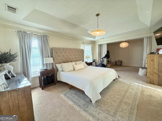 bedroom featuring visible vents, baseboards, ornamental molding, a tray ceiling, and carpet