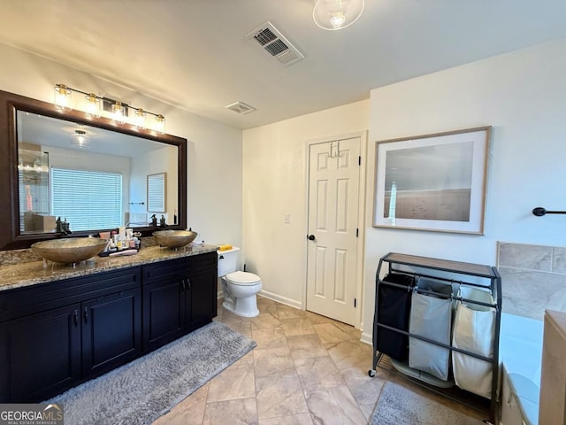 bathroom featuring visible vents, a sink, toilet, and double vanity