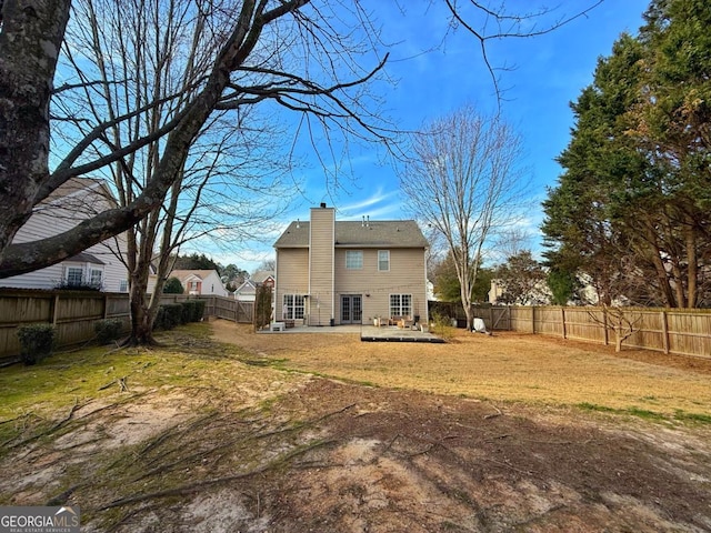 rear view of property featuring a patio area, a fenced backyard, a chimney, and a yard