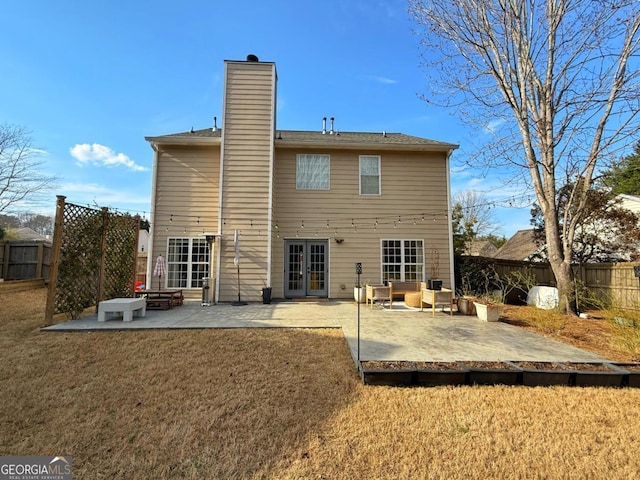 rear view of house with a patio area, a yard, a chimney, and french doors