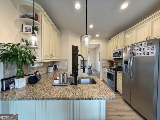 kitchen featuring a peninsula, a sink, appliances with stainless steel finishes, cream cabinetry, and backsplash