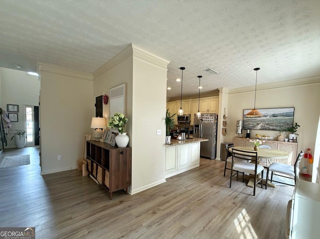 kitchen featuring light wood finished floors, appliances with stainless steel finishes, crown molding, and light stone countertops