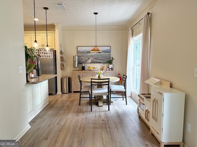 dining room with light wood-type flooring, crown molding, visible vents, and a textured ceiling