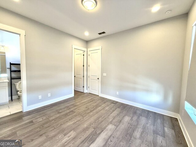 827 Winslow Way NW, Atlanta, GA 30318 - unfurnished bedroom featuring baseboards, connected bathroom, visible vents, and wood finished floors