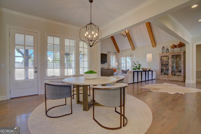 dining room featuring visible vents, lofted ceiling with beams, ornamental molding, wood finished floors, and an inviting chandelier