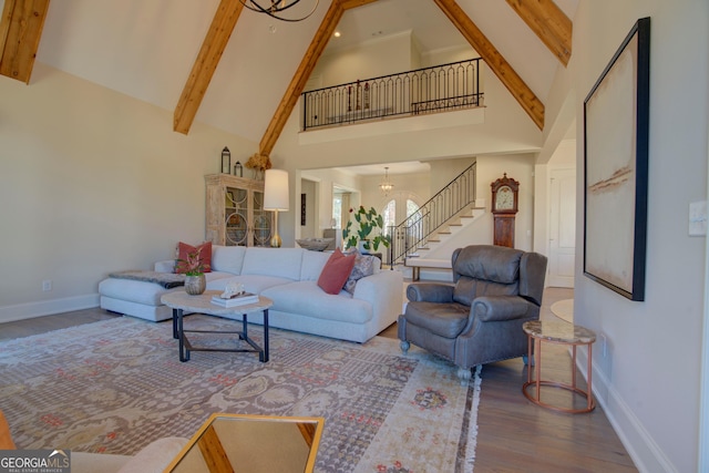 living area with a chandelier, high vaulted ceiling, wood finished floors, stairway, and beam ceiling