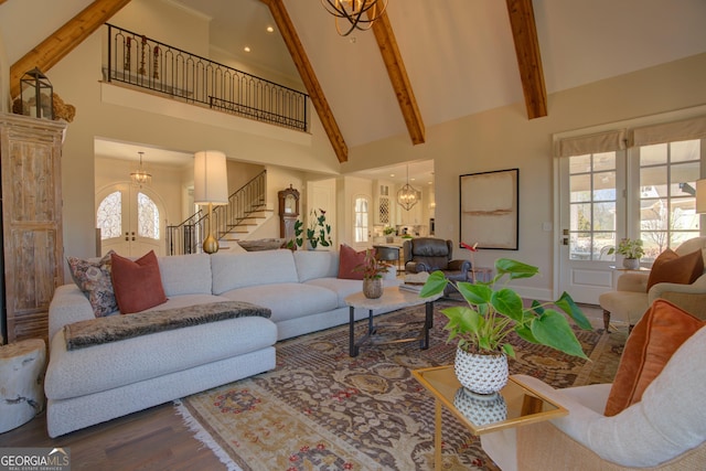 living room featuring high vaulted ceiling, french doors, stairway, beamed ceiling, and an inviting chandelier