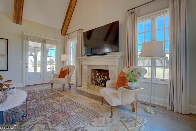 living area featuring baseboards, visible vents, a premium fireplace, wood finished floors, and vaulted ceiling with beams