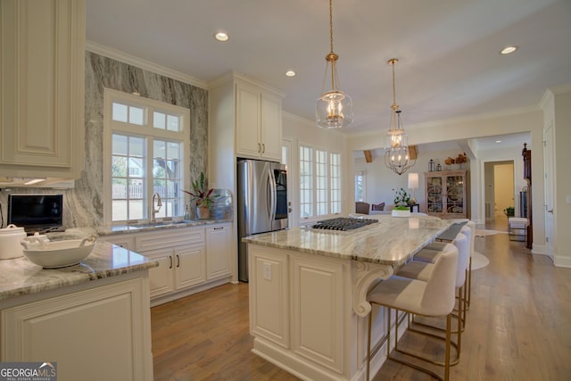 kitchen featuring crown molding, a sink, light stone counters, and a kitchen island