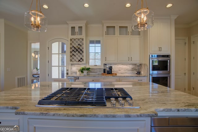 kitchen with an inviting chandelier, appliances with stainless steel finishes, white cabinets, and a center island