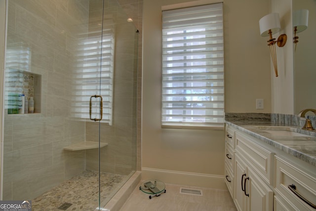 bathroom with tile patterned flooring, vanity, visible vents, baseboards, and a stall shower