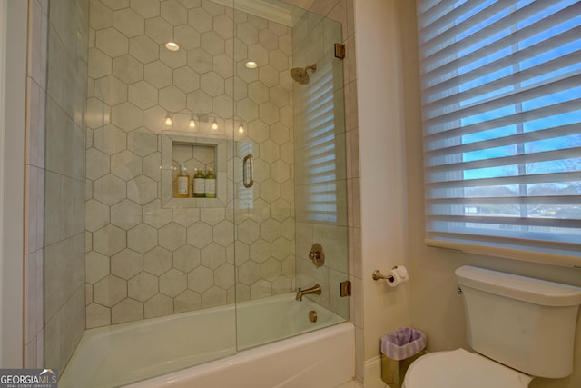 bathroom with toilet and bath / shower combo with glass door