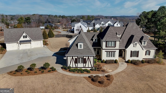 view of front of house featuring a garage, driveway, a shingled roof, and a residential view