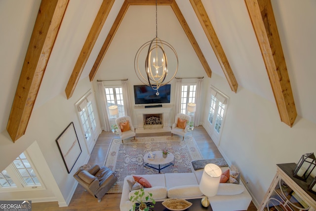 living room with a chandelier, high vaulted ceiling, a fireplace, wood finished floors, and beamed ceiling