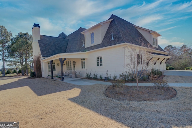 view of side of home featuring a patio and roof with shingles