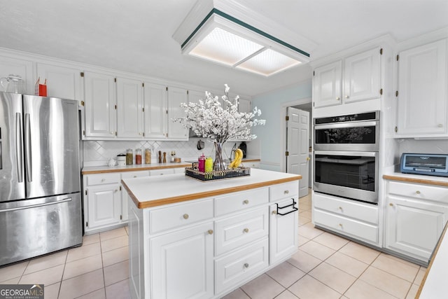 kitchen with stainless steel appliances, tasteful backsplash, light countertops, white cabinets, and light tile patterned flooring