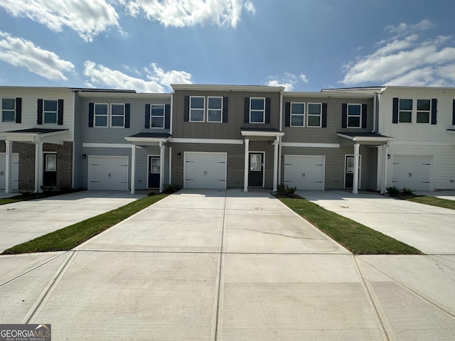 multi unit property with board and batten siding, driveway, and an attached garage