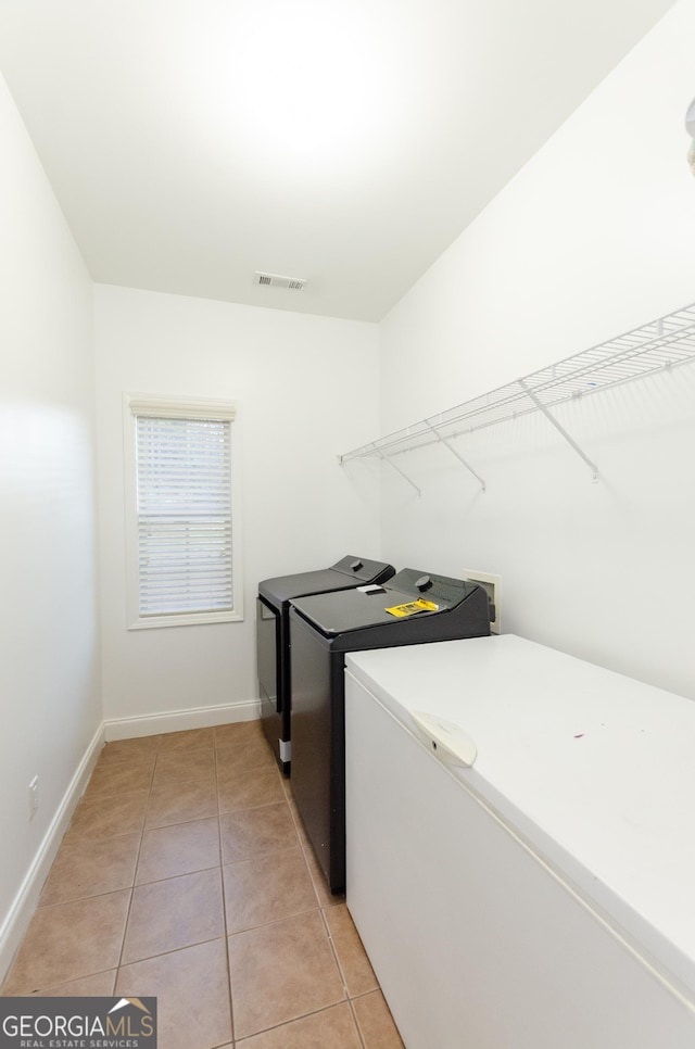 2474 Starfire Ln, Loganville, GA 30052 - laundry room featuring washer and clothes dryer, light tile patterned flooring, and baseboards