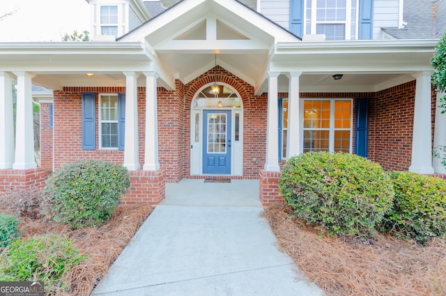 entrance to property with a porch and brick siding