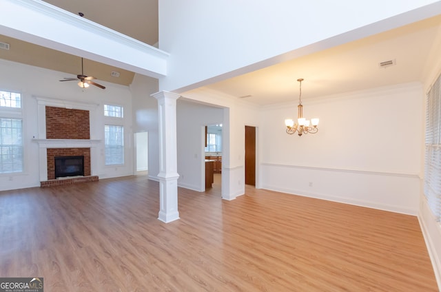 2474 Starfire Ln, Loganville, GA 30052 - unfurnished living room featuring a ceiling fan, light wood finished floors, a chandelier, baseboards, and a fireplace