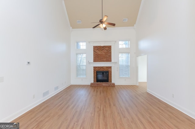 2474 Starfire Ln, Loganville, GA 30052 - unfurnished living room featuring ornamental molding, a towering ceiling, ceiling fan, light wood finished floors, and baseboards