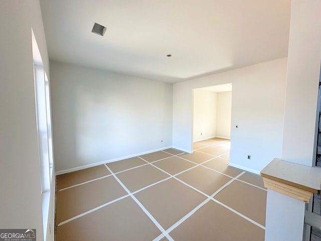 spare room with tile patterned flooring and baseboards