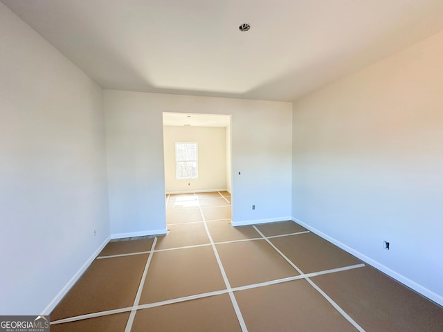 tiled spare room featuring baseboards