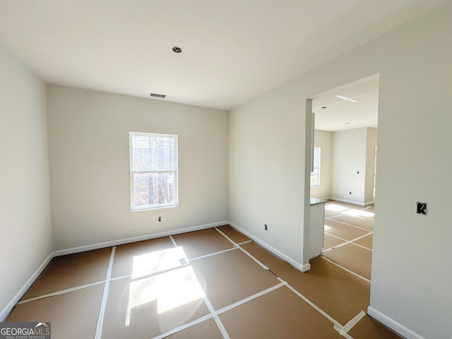 empty room featuring a healthy amount of sunlight, baseboards, and visible vents