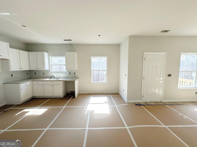 kitchen featuring baseboards, white cabinetry, and light countertops