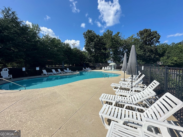 community pool with a patio area and fence