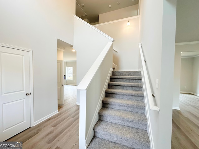 stairway with crown molding, baseboards, and wood finished floors