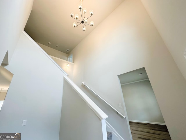 stairway featuring a chandelier, a high ceiling, wood finished floors, and baseboards