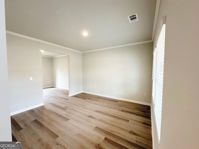 unfurnished room featuring ornamental molding, wood finished floors, visible vents, and baseboards