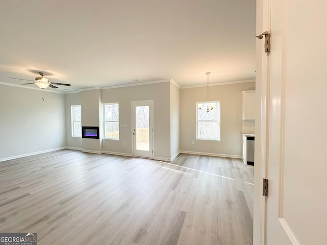 unfurnished living room featuring ornamental molding, a glass covered fireplace, baseboards, and light wood finished floors